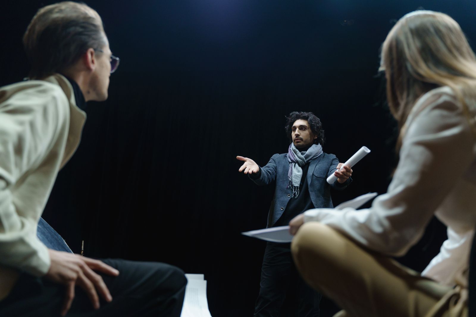 Theater director coaching two actors mid-scene during a rehearsal, scripts in hand — the same rehearse-feedback-repeat loop that drives roleplay training